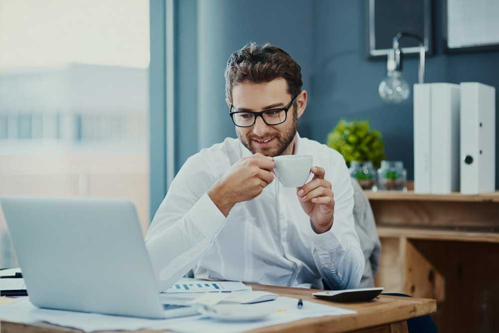 Mann mit Brille freut sich am Laptop über das Arbeitsergebnis, symbolisiert Erfolg durch hochwertige Übersetzungen