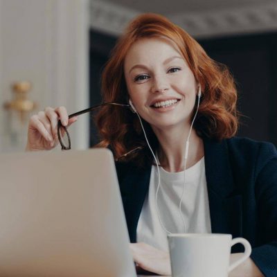 Zufriedene Nutzerin mit Headset am Laptop, freut sich über den schnellen und professionellen Übersetzungsservice